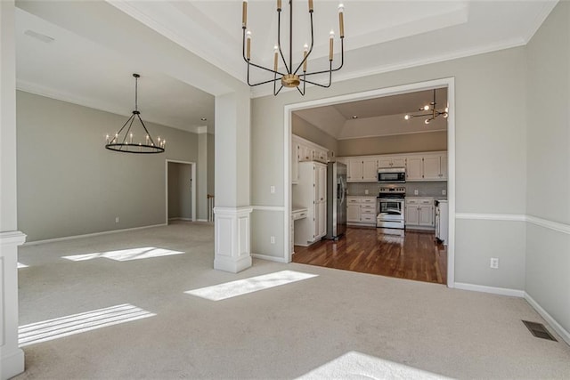 unfurnished dining area with an inviting chandelier, dark carpet, a tray ceiling, and crown molding