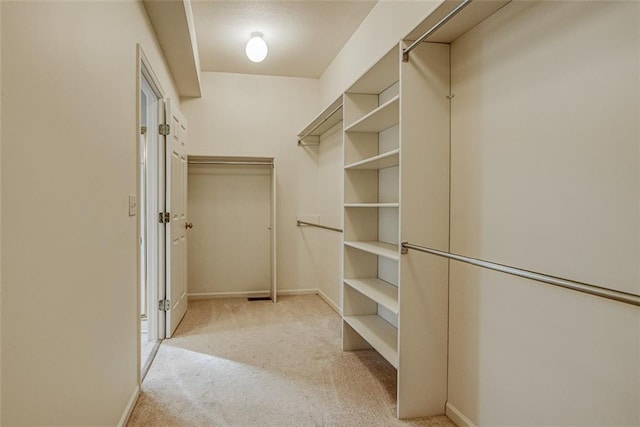 walk in closet with light colored carpet