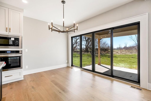 unfurnished dining area with a wealth of natural light, visible vents, a chandelier, and light wood-style floors