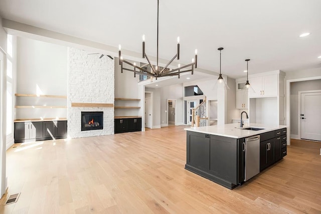 kitchen featuring light countertops, a sink, dark cabinetry, stainless steel dishwasher, and visible vents