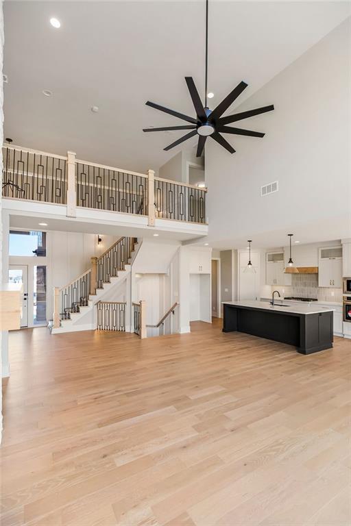 unfurnished living room with a sink, visible vents, light wood-style floors, and a ceiling fan