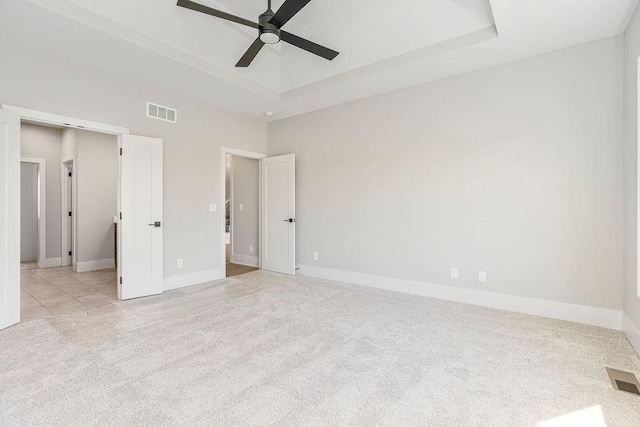 unfurnished bedroom with a raised ceiling, carpet floors, baseboards, and visible vents