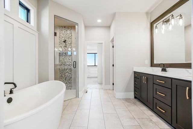full bathroom featuring tile patterned flooring, vanity, baseboards, a shower stall, and a soaking tub