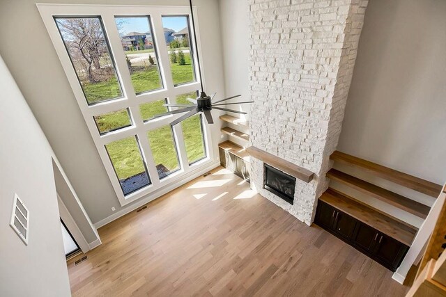 living area featuring visible vents, wood finished floors, a glass covered fireplace, and a healthy amount of sunlight