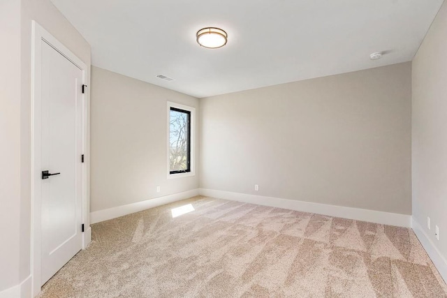 spare room with light colored carpet, visible vents, and baseboards