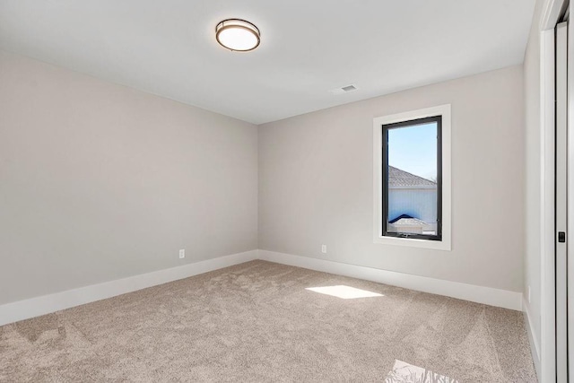 carpeted spare room featuring baseboards and visible vents