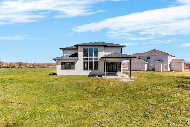 back of house with a lawn, roof with shingles, and a patio