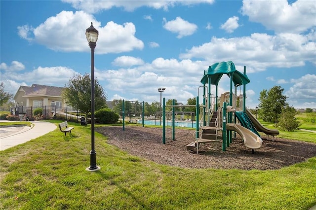 community play area featuring fence and a lawn