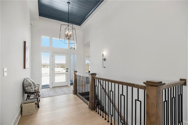 entrance foyer with a chandelier, a tray ceiling, and light wood-type flooring