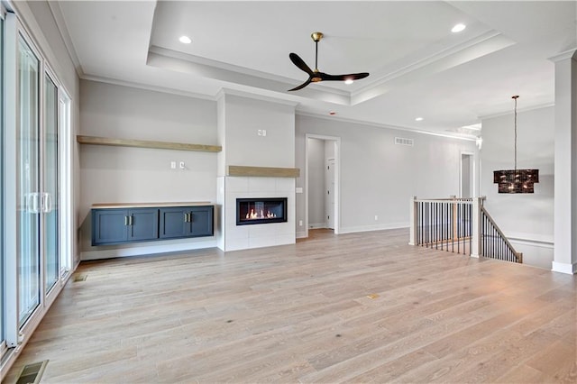 24940 W 98th Pl, Lenexa, KS 66227 - unfurnished living room featuring crown molding, a raised ceiling, ceiling fan, light wood-style flooring, and a chandelier