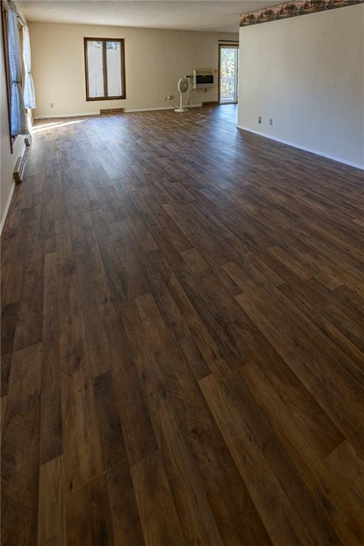 unfurnished room featuring dark hardwood / wood-style flooring, a wall mounted air conditioner, and a wealth of natural light