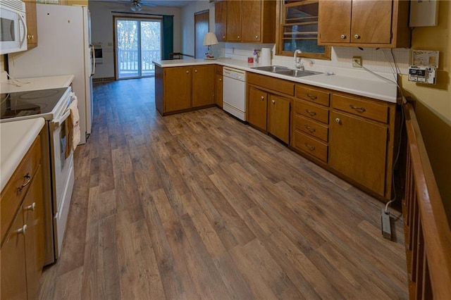 kitchen with white appliances, sink, kitchen peninsula, ceiling fan, and dark wood-type flooring