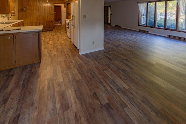 kitchen featuring dark wood-type flooring, wood walls, sink, and range