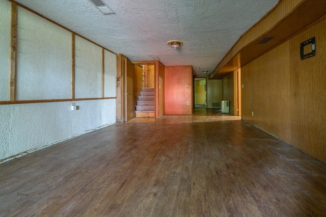 unfurnished room with hardwood / wood-style flooring, a textured ceiling, and wooden walls