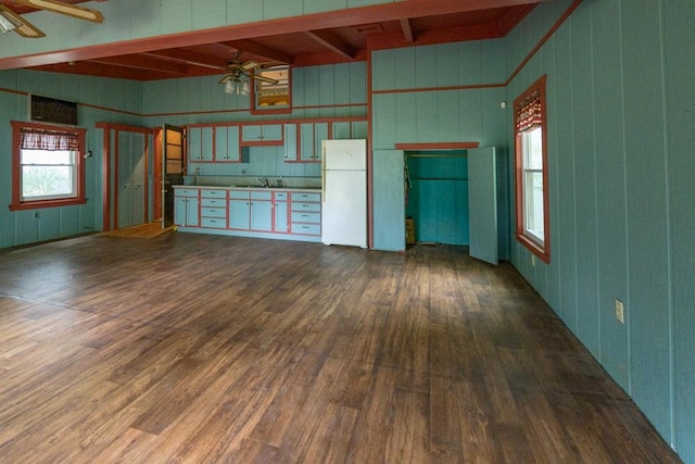 unfurnished living room with dark wood-type flooring, ceiling fan, beamed ceiling, and sink