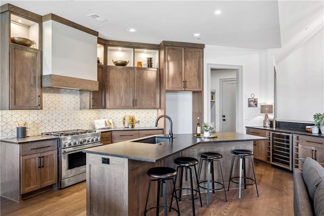 13707 Pembroke Ln, Leawood, KS 66224 - kitchen with wine cooler, dark countertops, wood finished floors, high end stainless steel range oven, and a sink