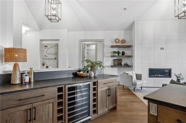 13707 Pembroke Ln, Leawood, KS 66224 - bar with a tile fireplace, wine cooler, wood finished floors, pendant lighting, and a chandelier