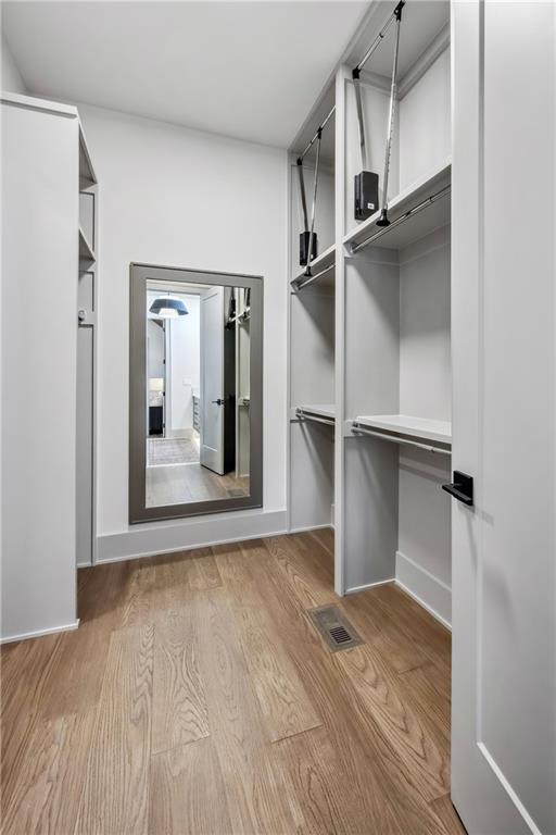 13707 Pembroke Ln, Leawood, KS 66224 - walk in closet featuring wood finished floors and visible vents