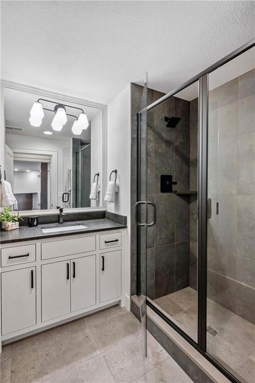 13707 Pembroke Ln, Leawood, KS 66224 - bathroom featuring a shower stall, a textured ceiling, and vanity