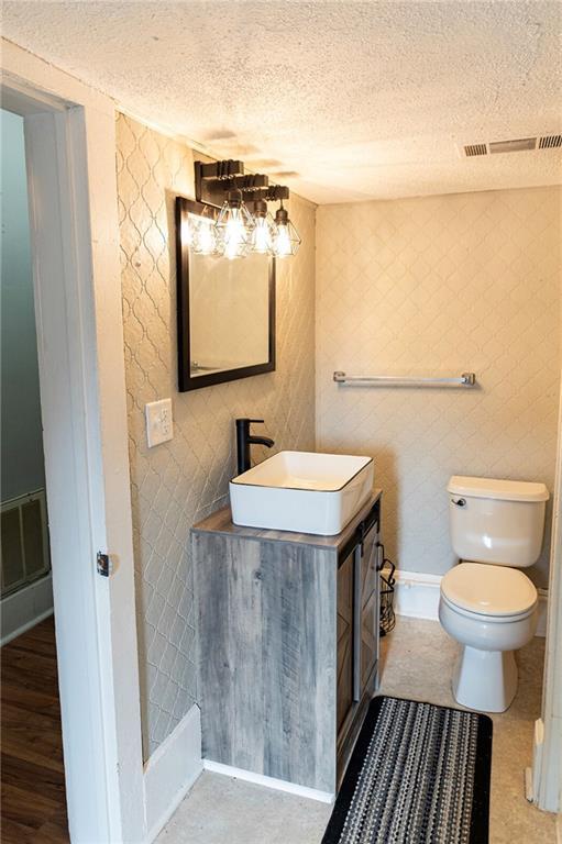 bathroom with a textured ceiling, vanity, toilet, and hardwood / wood-style flooring