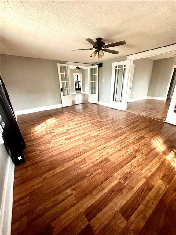 interior space featuring a textured ceiling, hardwood / wood-style floors, ceiling fan, and french doors