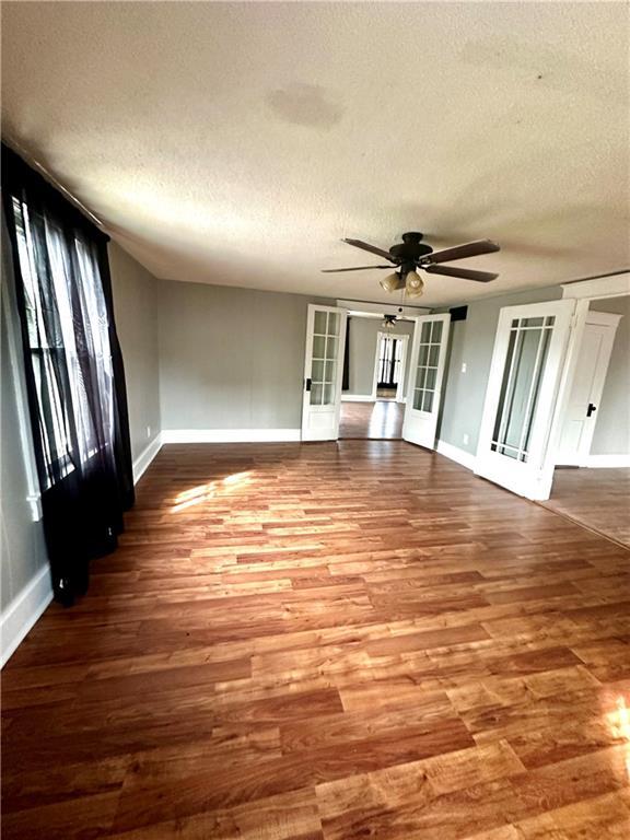 interior space featuring a textured ceiling, wood-type flooring, ceiling fan, and french doors