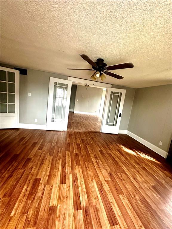 spare room featuring a textured ceiling, wood-type flooring, and ceiling fan