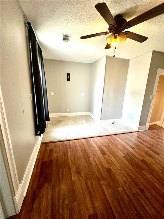 spare room featuring ceiling fan, hardwood / wood-style flooring, and a textured ceiling