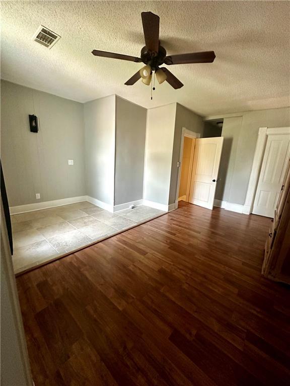 unfurnished bedroom featuring ceiling fan, hardwood / wood-style flooring, and a textured ceiling