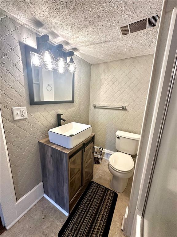 bathroom with a textured ceiling, vanity, and toilet