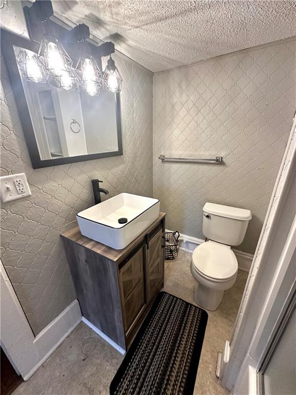 bathroom featuring vanity, toilet, and a textured ceiling