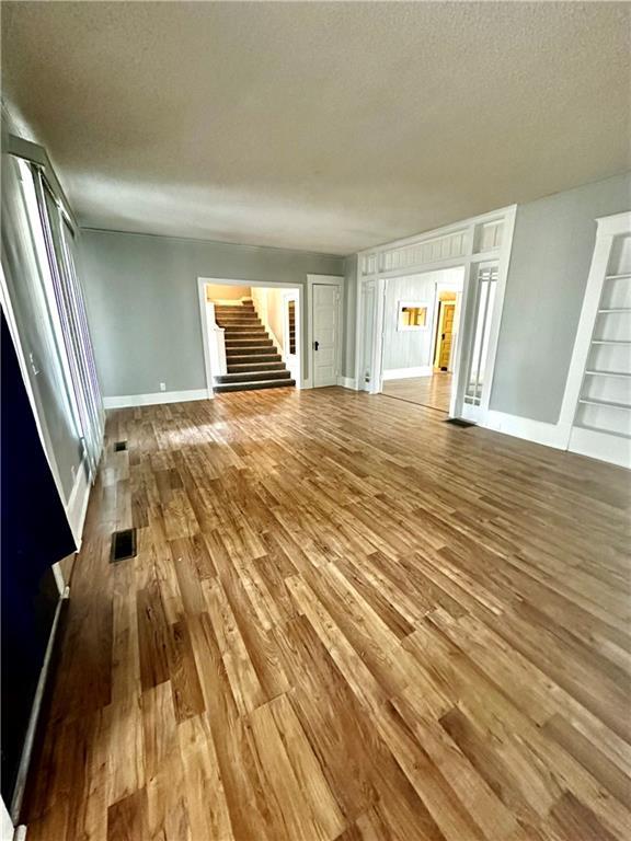 unfurnished living room featuring a textured ceiling, hardwood / wood-style flooring, and built in features