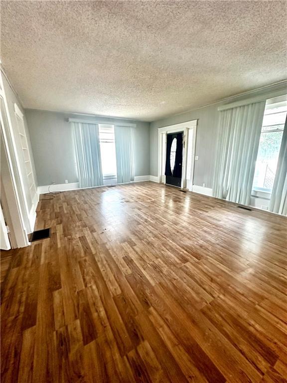 unfurnished living room featuring a textured ceiling and hardwood / wood-style floors