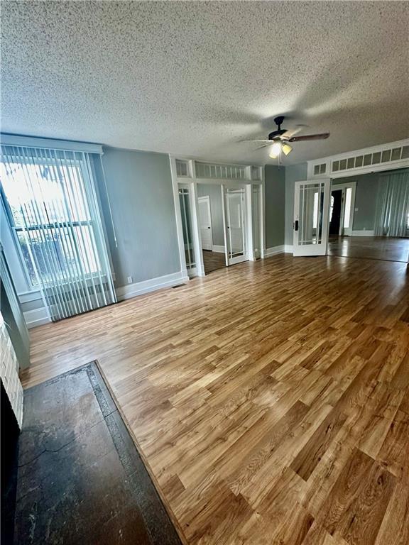 unfurnished living room featuring ceiling fan, a textured ceiling, and hardwood / wood-style floors