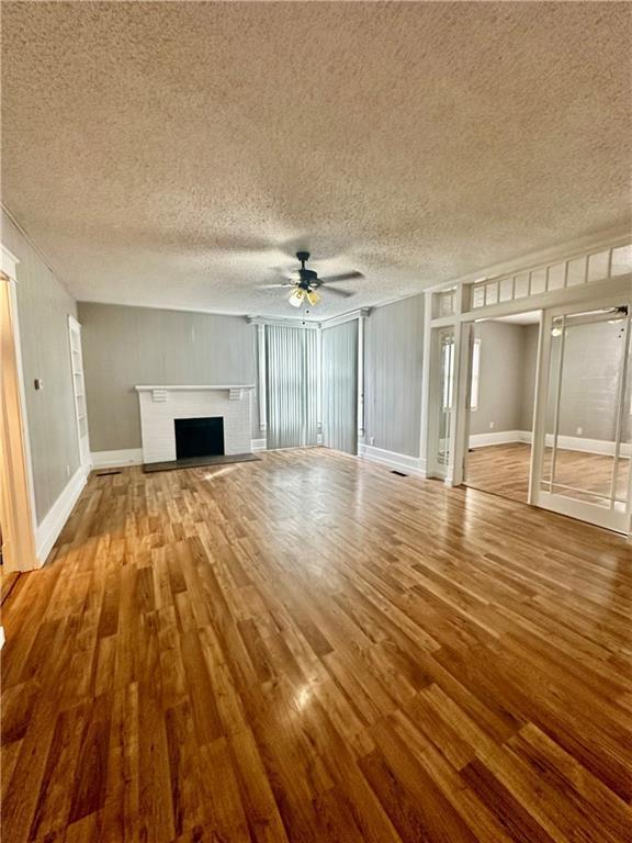 unfurnished living room featuring ceiling fan, a textured ceiling, and hardwood / wood-style floors