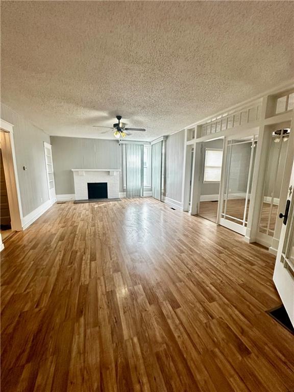 unfurnished living room with ceiling fan, a textured ceiling, and hardwood / wood-style floors