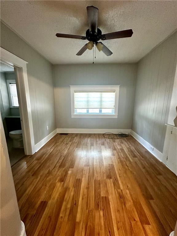 spare room featuring a textured ceiling, wood-type flooring, and ceiling fan