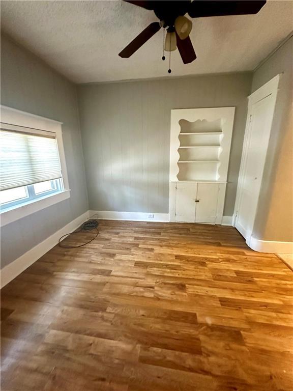 unfurnished bedroom featuring ceiling fan, a textured ceiling, and light wood-type flooring