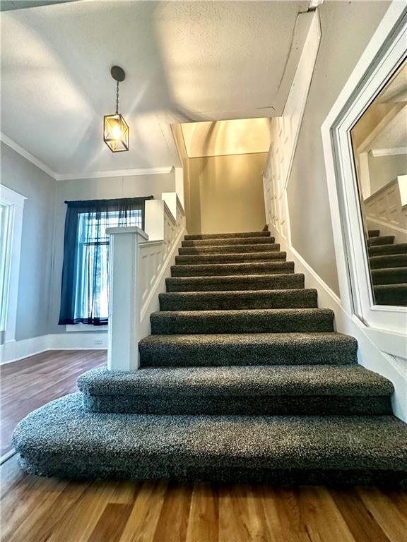 staircase featuring crown molding and hardwood / wood-style floors