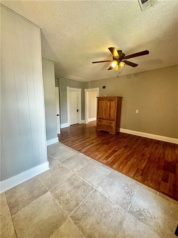 unfurnished room featuring ceiling fan, a textured ceiling, and light hardwood / wood-style flooring