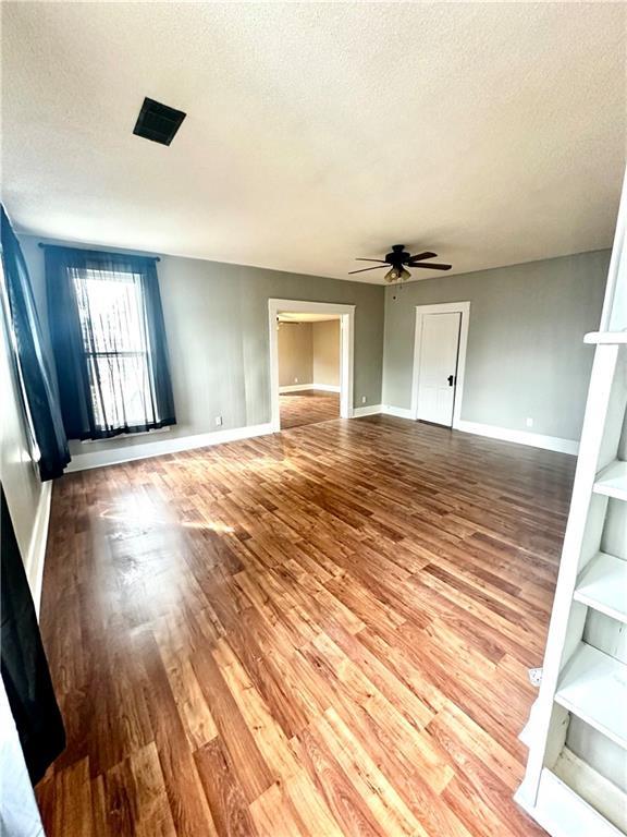 unfurnished living room featuring a textured ceiling, wood-type flooring, and ceiling fan