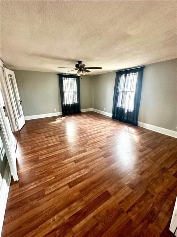 empty room featuring a textured ceiling, dark hardwood / wood-style floors, and a wealth of natural light