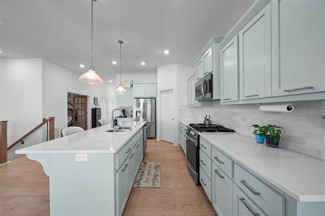 kitchen featuring appliances with stainless steel finishes, a breakfast bar, pendant lighting, sink, and a center island with sink