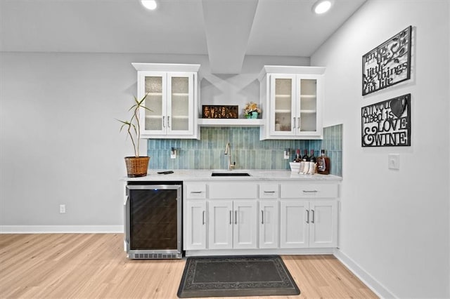 bar with wine cooler, sink, decorative backsplash, and white cabinets