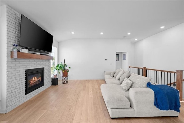 living room with a fireplace, vaulted ceiling, and light hardwood / wood-style flooring