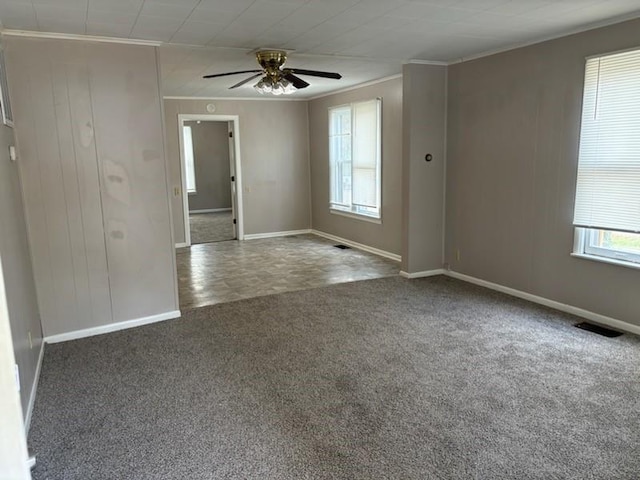 empty room featuring crown molding, dark carpet, and ceiling fan