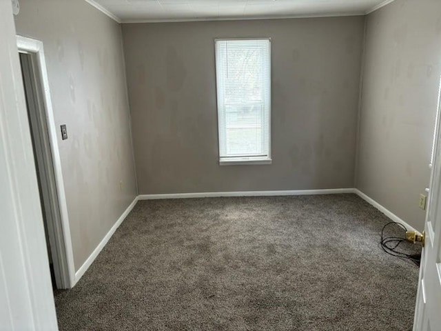 spare room with dark colored carpet, a wealth of natural light, and crown molding