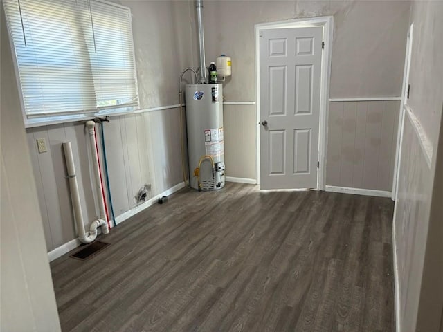 clothes washing area with water heater and dark wood-type flooring