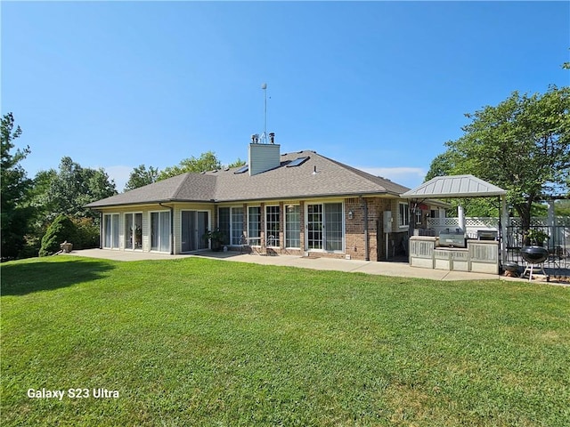 rear view of property featuring area for grilling, a patio, and a lawn