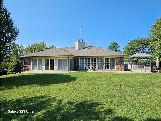 back of property with a gazebo, a patio area, and a lawn